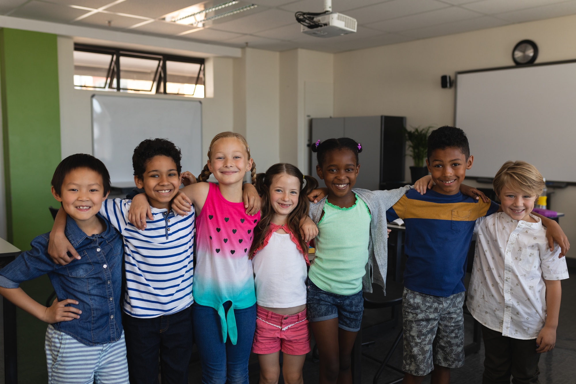 Happy school kids standing and looking at camera in classroom of elementary school